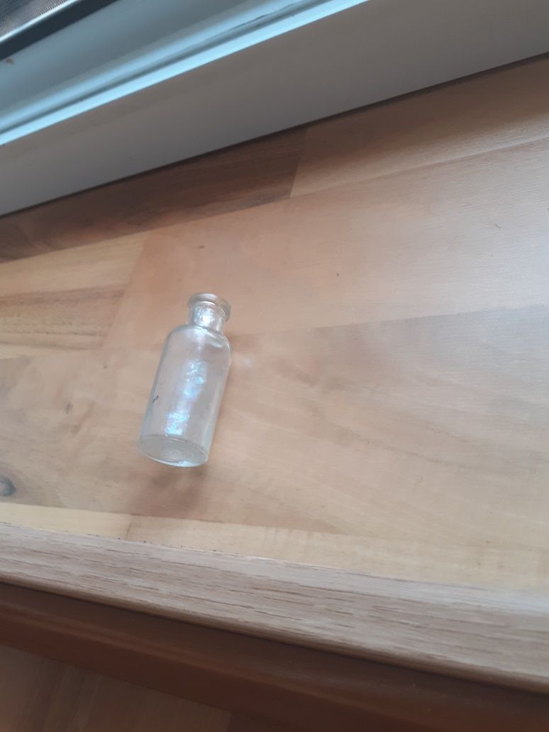 Szklany pojemnik na lekarstwa oraz mała buteleczka.