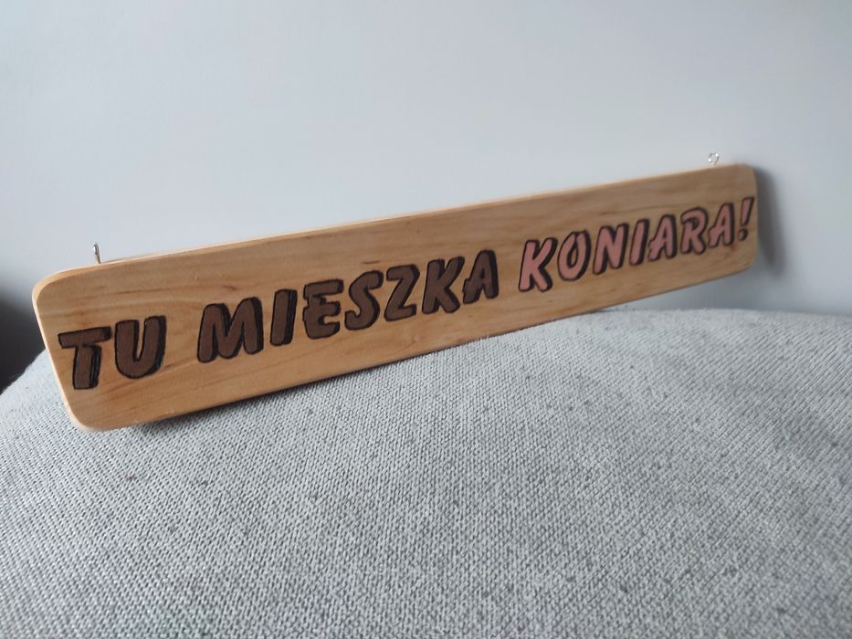 Drewniana tabliczka zawieszana z napisem: Tu mieszka koniata!