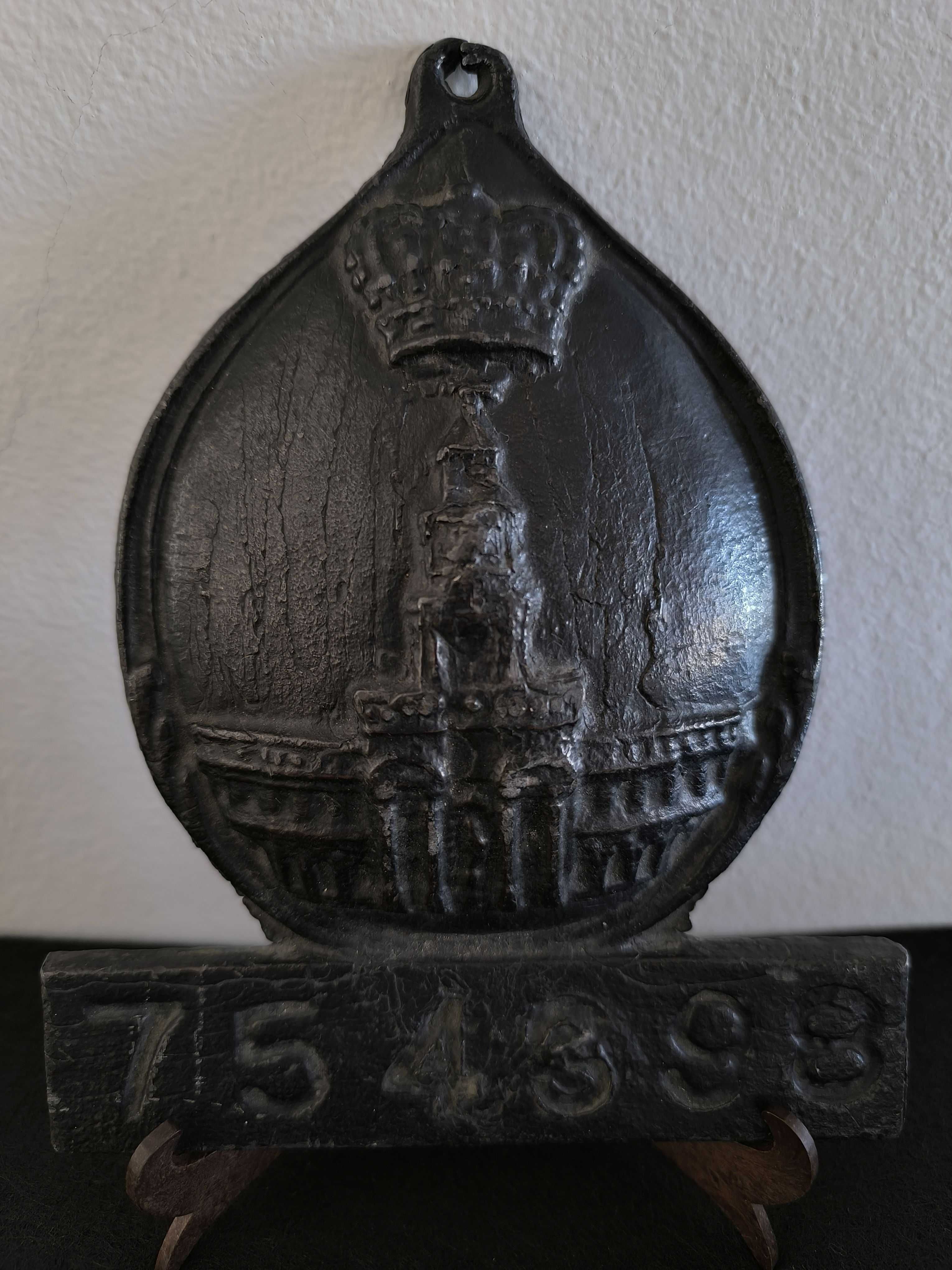 Placa de metal com o n.º 754398, marcada com o emblema da seguradora