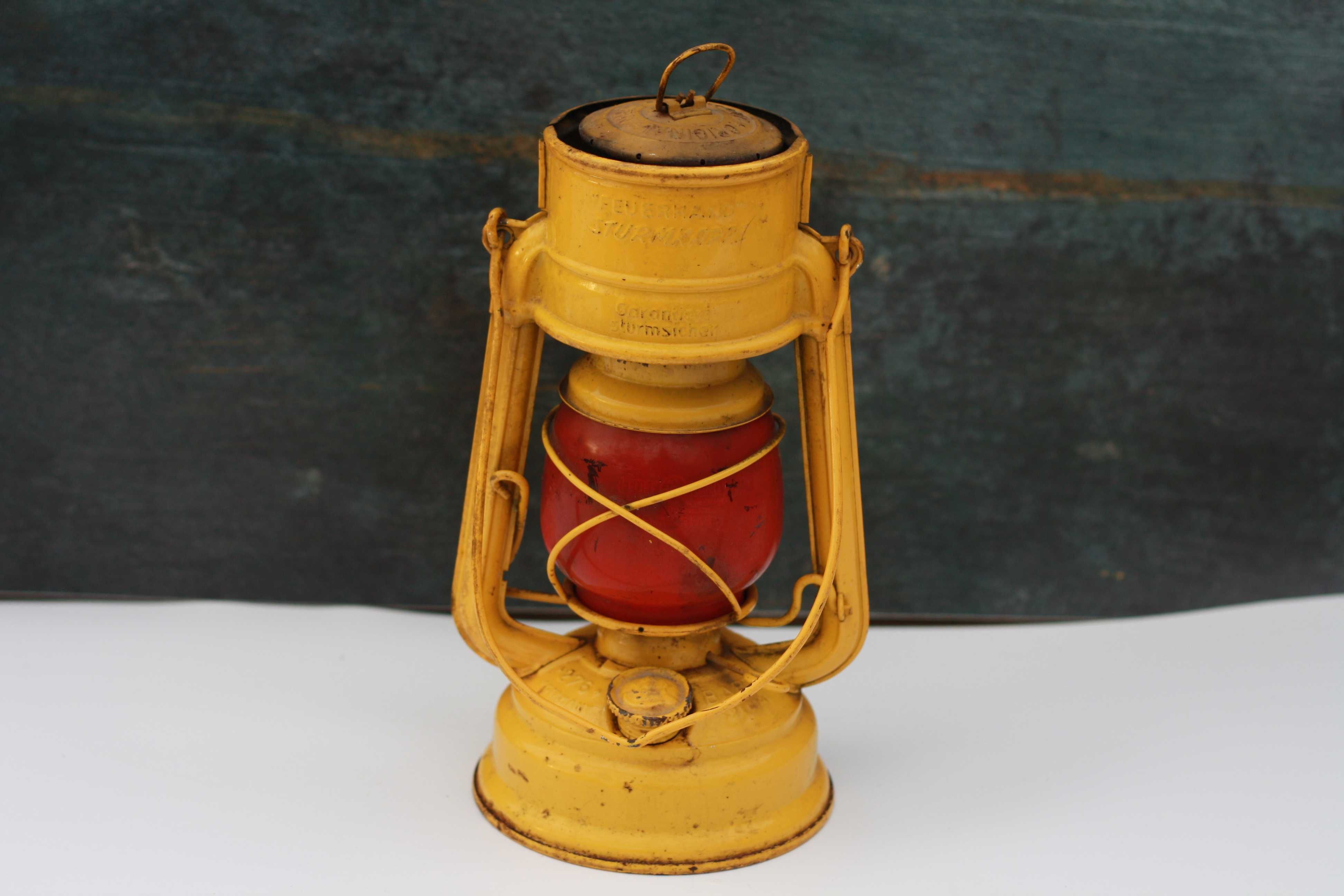 Żółta lampa naftowa Feuerhand Sturmkappe z czerwonym kloszem vintage