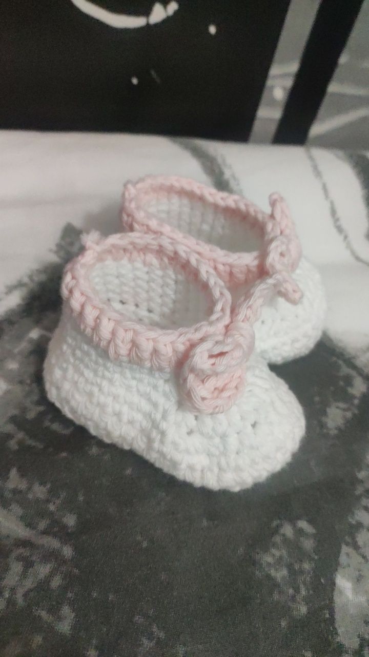 Białe własnoręcznie robione buciki niemowlęce