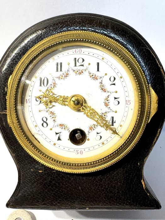 Antigo relógio de viagem com mostrador esmaltado e caixa em couro