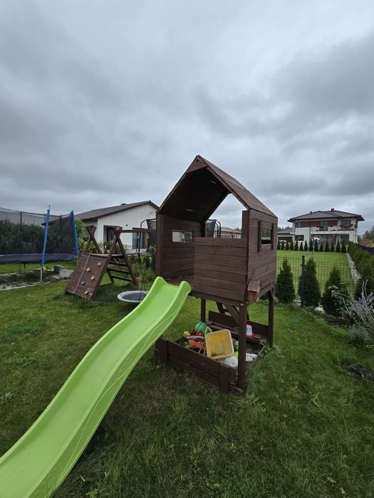 Drewniany plac zabaw z domkiem, zjeżdżalnią, huśtawką i ścianką wspina