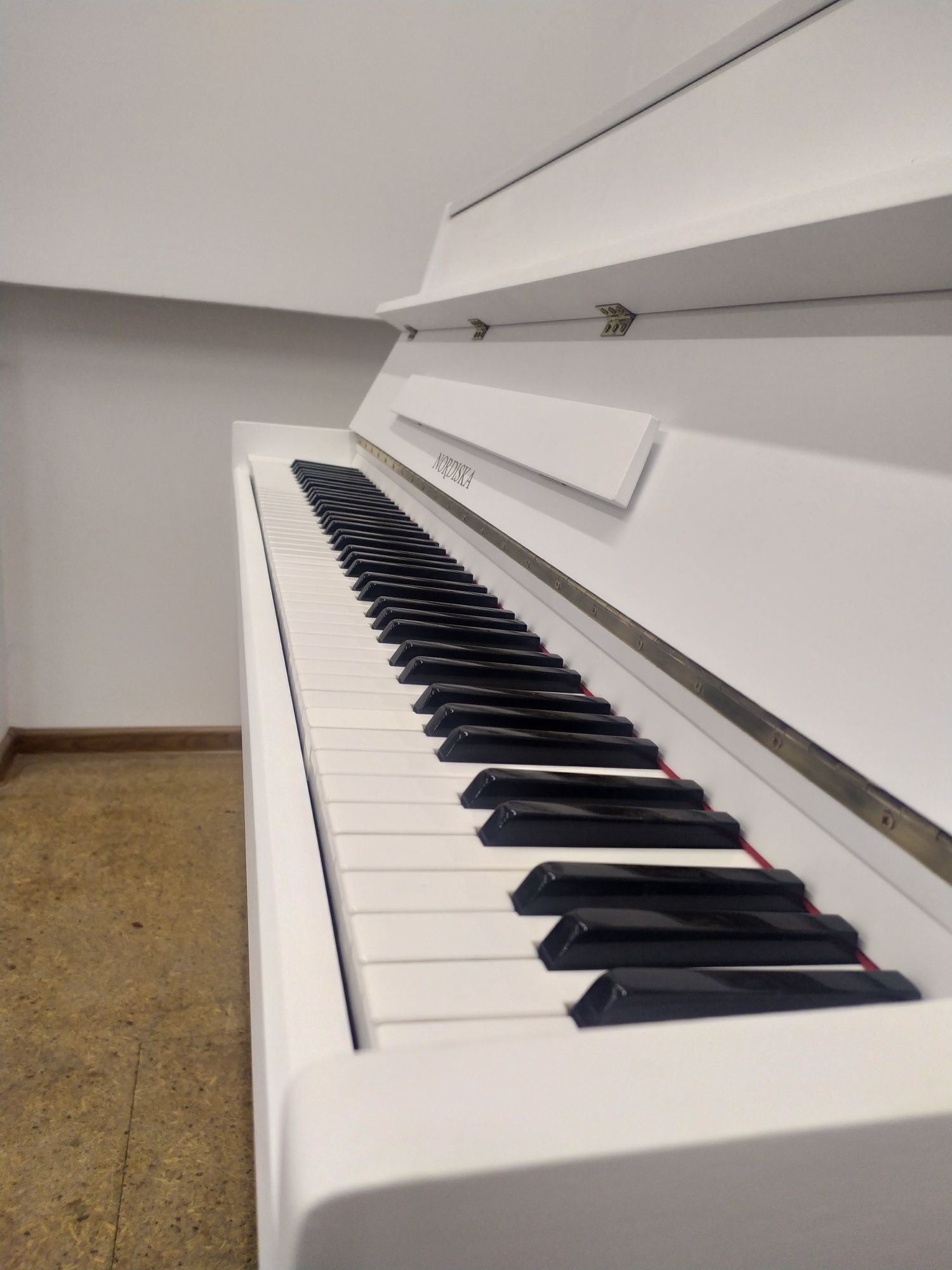 Białe pianino Nordiska z mechanizmem Renner
