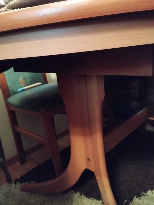 Owalny, rozkładany stół do salonu lub jadalni z krzesłami.