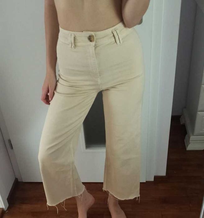 Kremowe spodnie z rozszerzanymi nogawkami, podkreślające sylwetkę