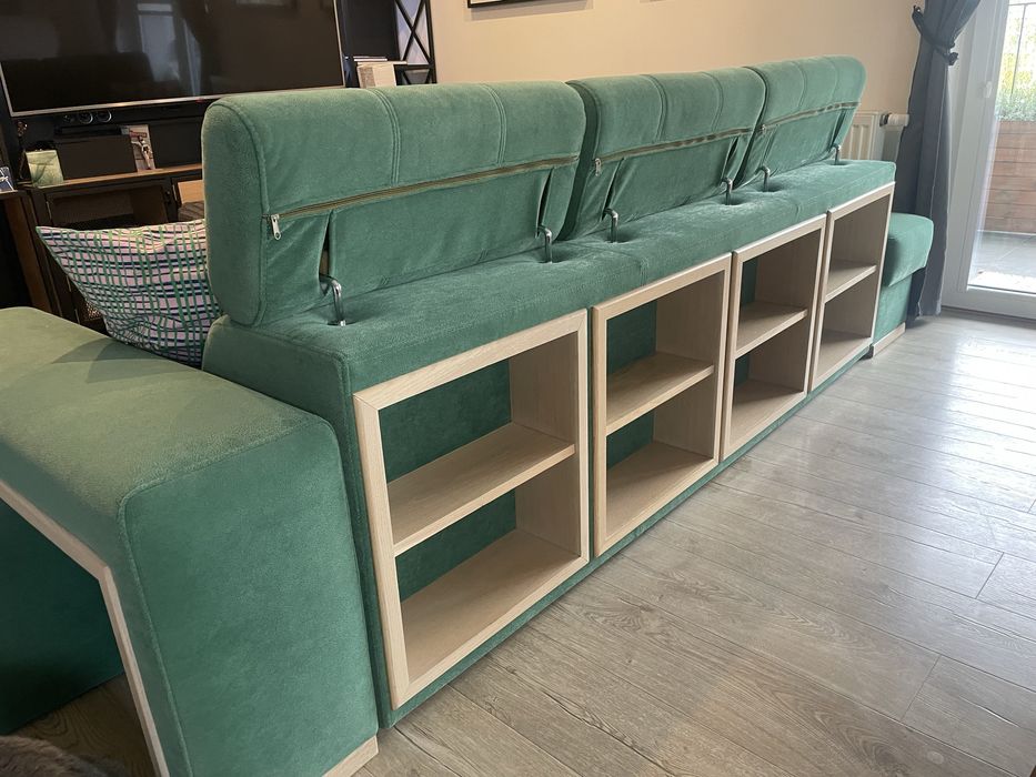 Zielona butelkowa sofa z funkcja spania z pufami i drewnianymi półkami