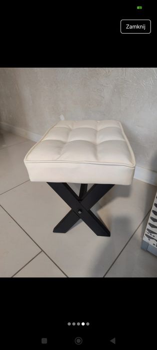 tapicerowana pufa lub podnóżek z podstawą w kształcie litery X.