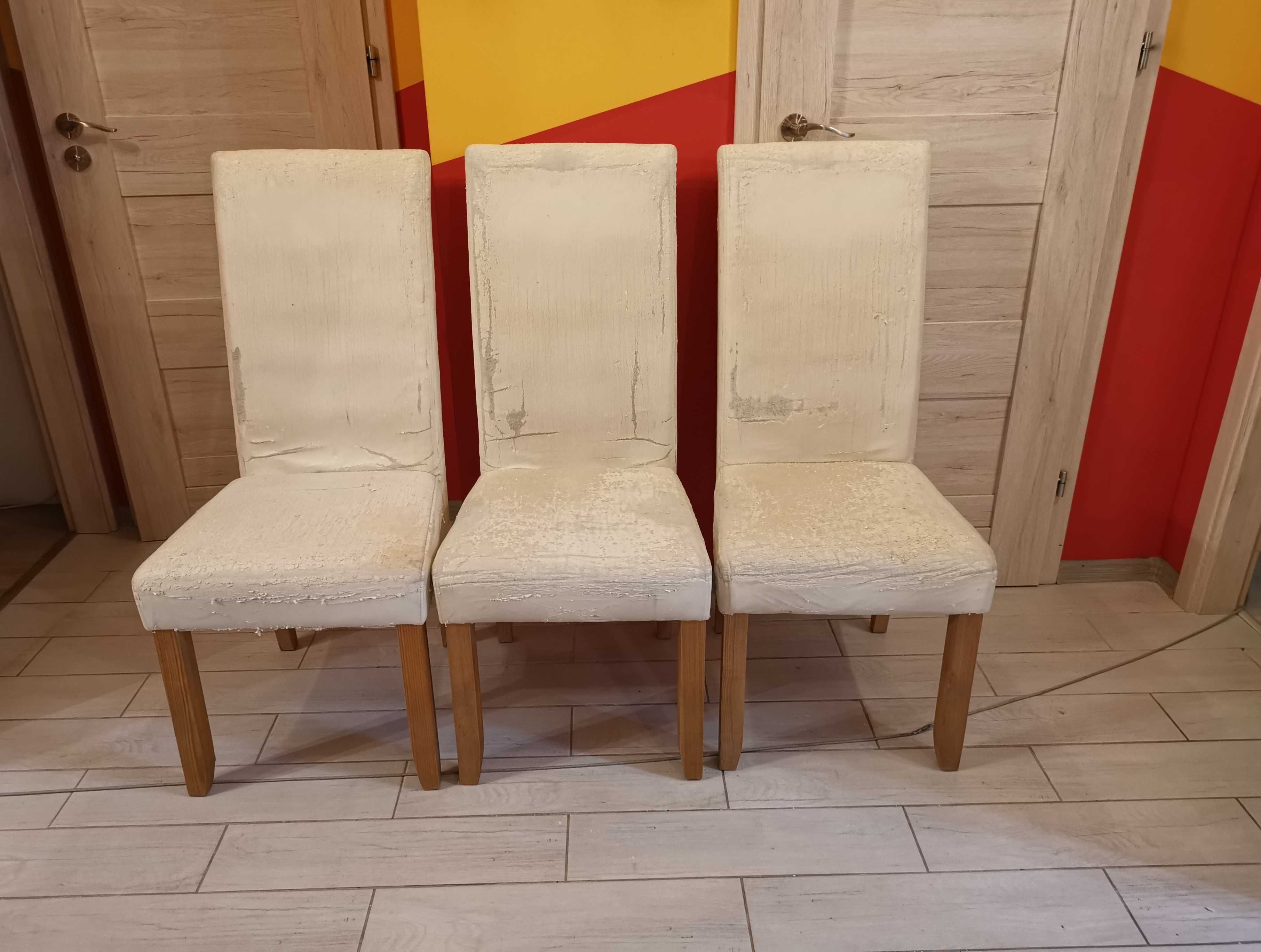 Trzy białe skórzane krzesła z pokrowcami