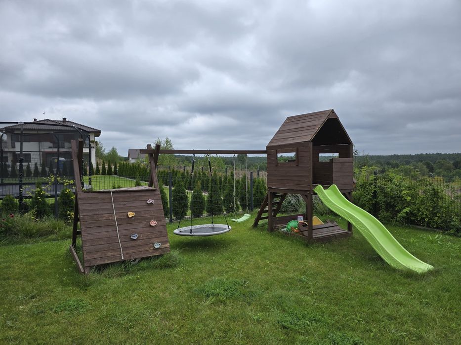 Drewniany plac zabaw z domkiem, zjeżdżalnią, huśtawką i ścianką wspina