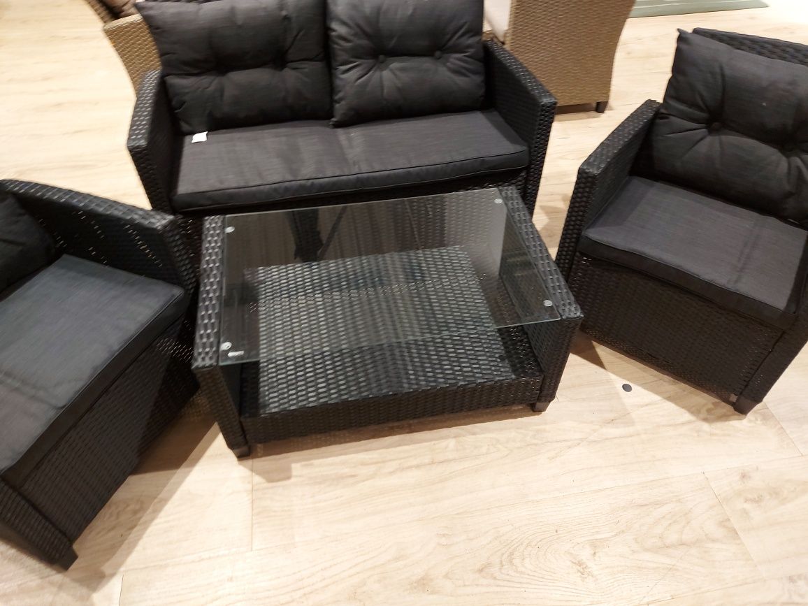 Meble ogrodowe sofa plus dwa fotele i stolik z drewnianym blatem.