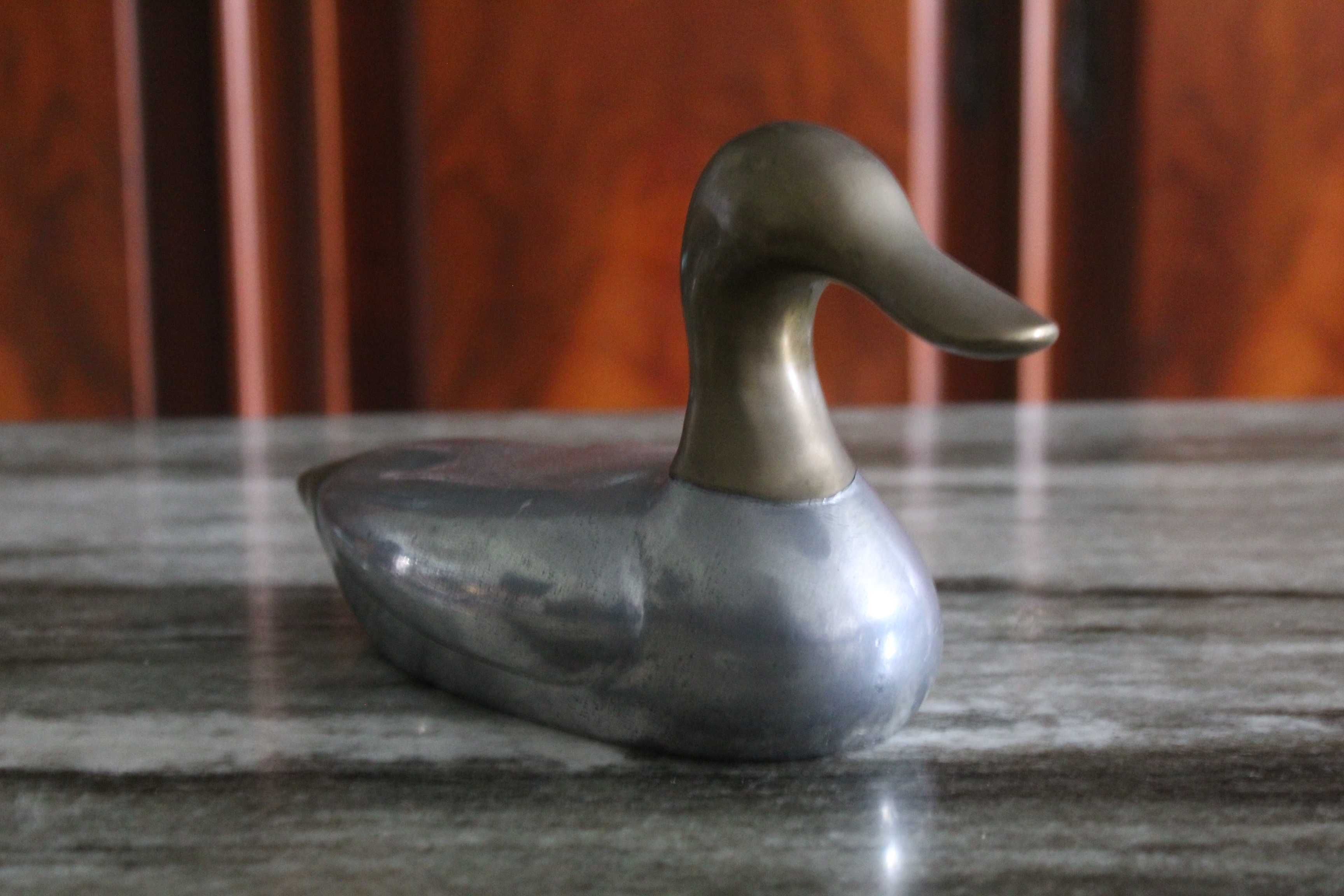 Estatueta vintage de pato, corpo prateado e a cabeça e cauda douradas.