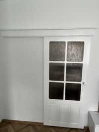 Białe drewniane drzwi przesuwne z maskownicą