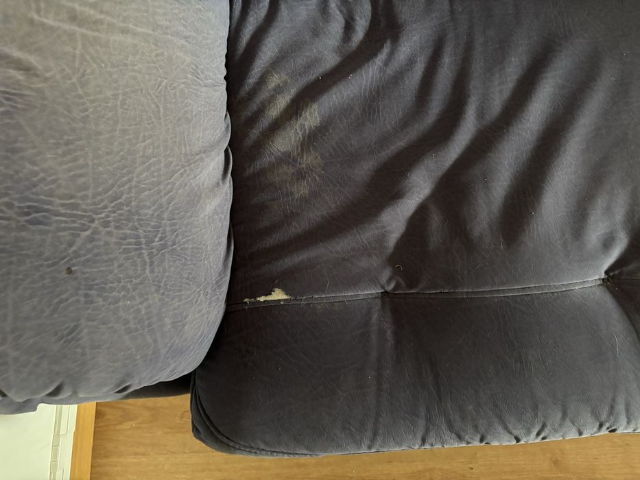 Sofá de sala, azul, com alguns anos e marcas de uso.