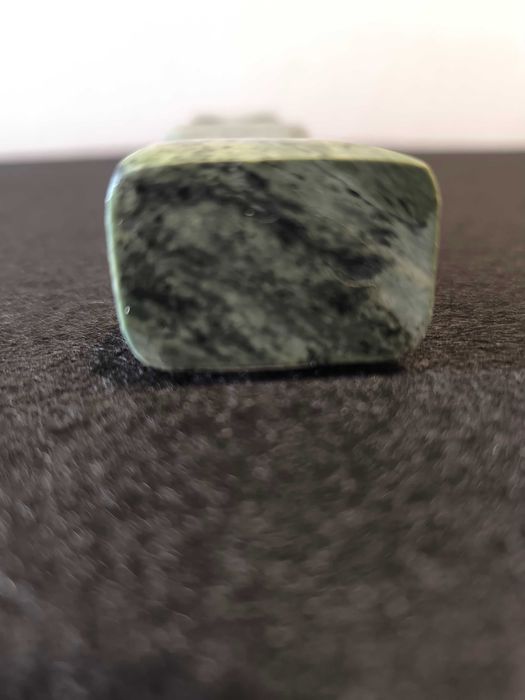 Escultura de mulher em pedra de cor verde.