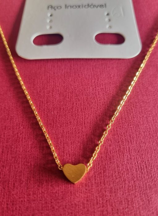 Colar dourado, em aço, com pequeno coração fixo. Tem extensor