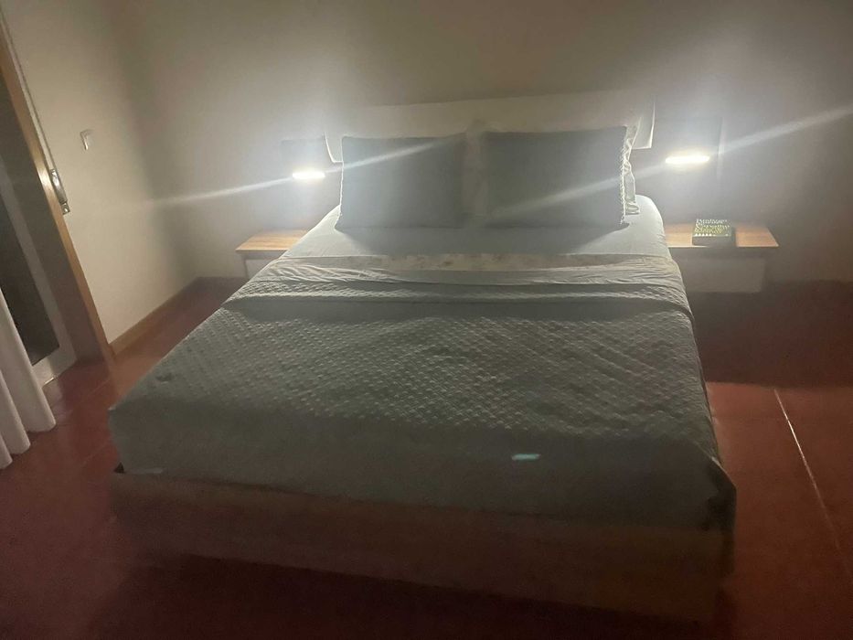 Cama de casal com mesas de cabeceira e iluminação