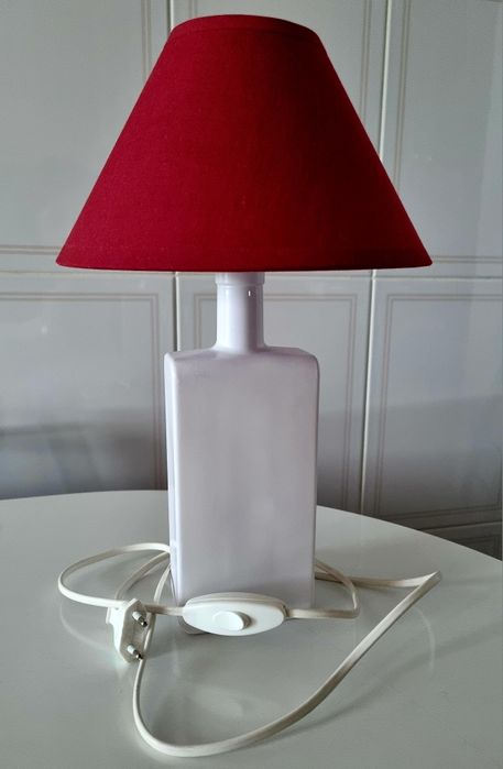 Candeeiro de mesa, feito com uma garrafa branca e abajour vermelho.
