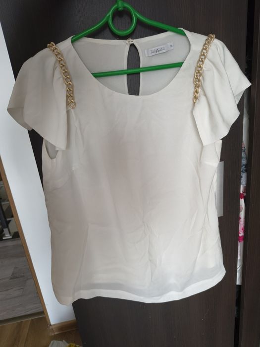 Elegancka ecru bluzka ze złotymi łańcuszkami falbany na ramionach