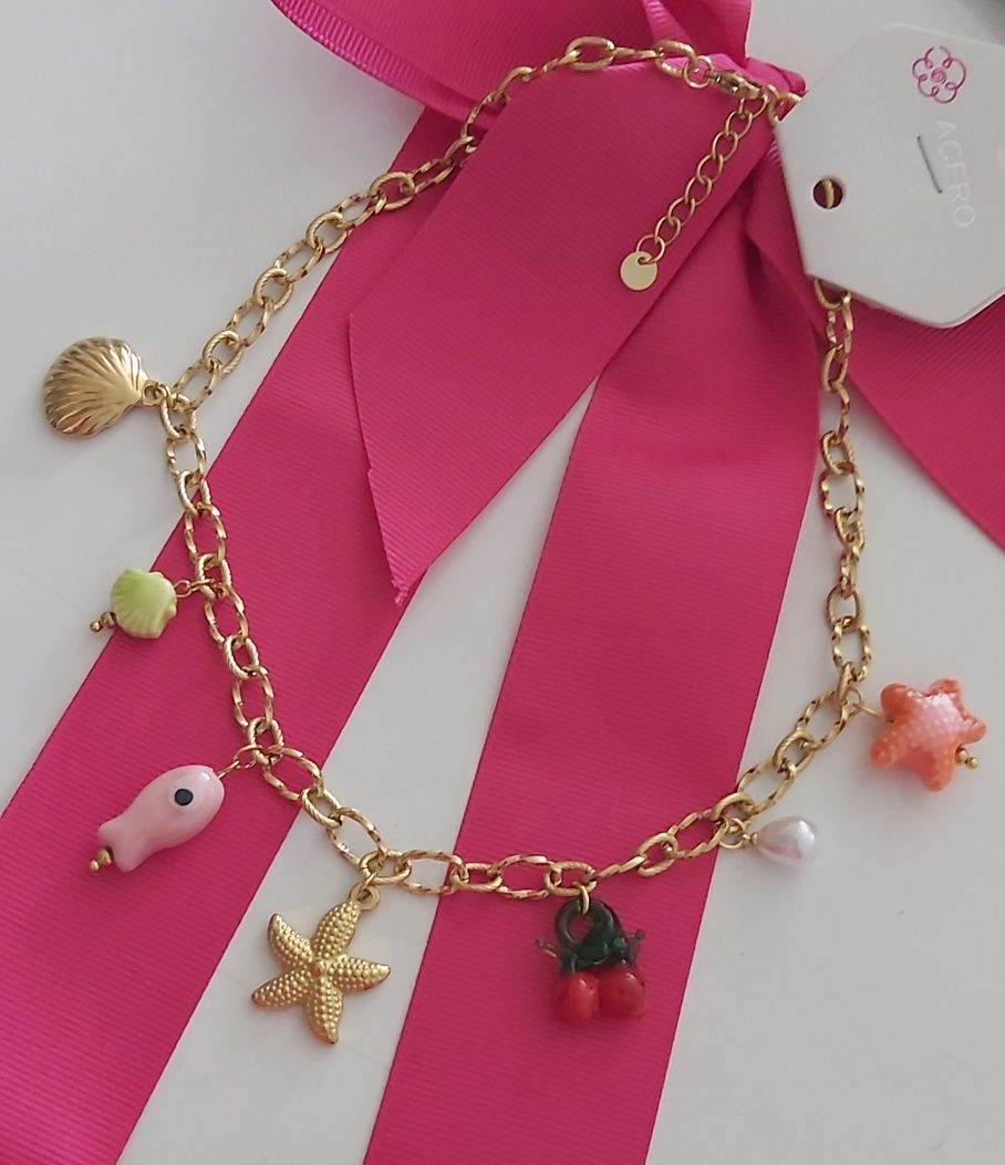 Colar dourado, em aço, com 7 pingentes diferentes. Tem extensor