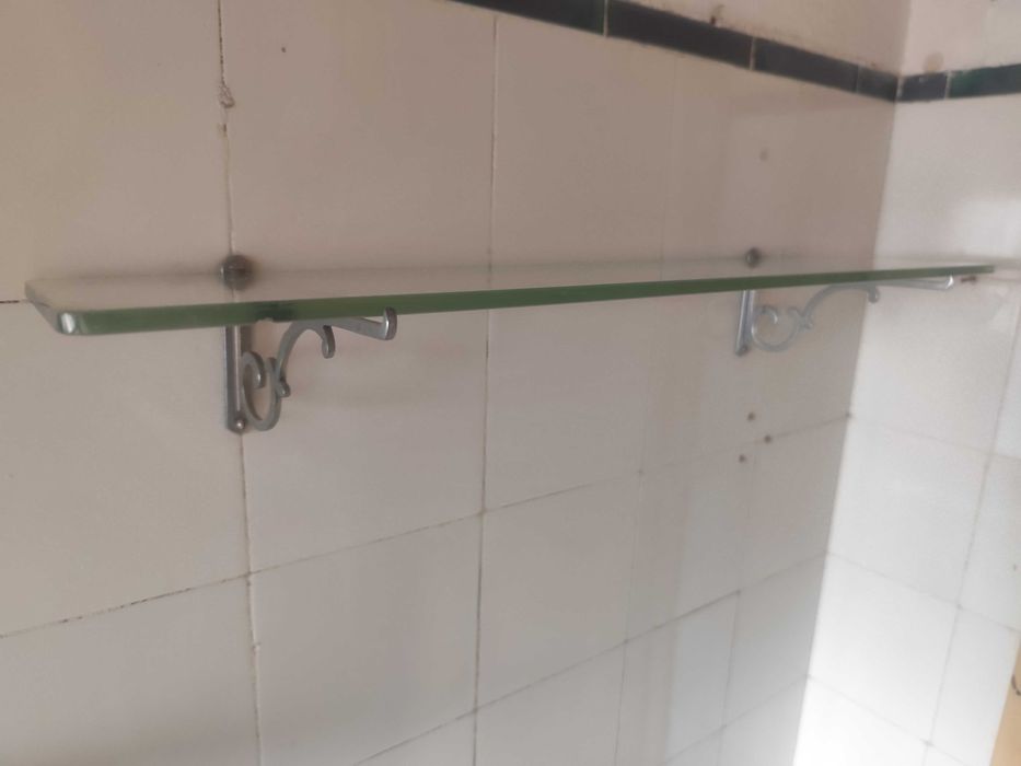 Prateleira de casa de banho em vidro com poleias metálicas.