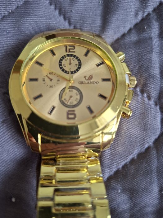 Duży zegarek w kolorze złotym z bransoletką.