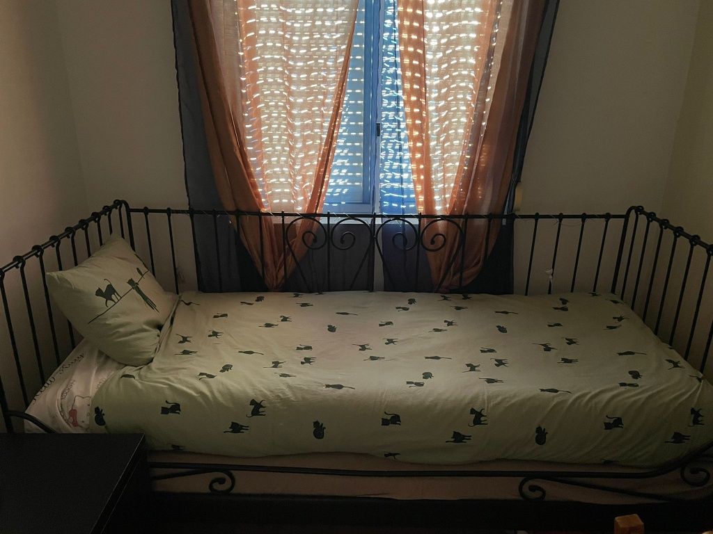 Cama de ferro preta com colchões e mesa de cabeceira
