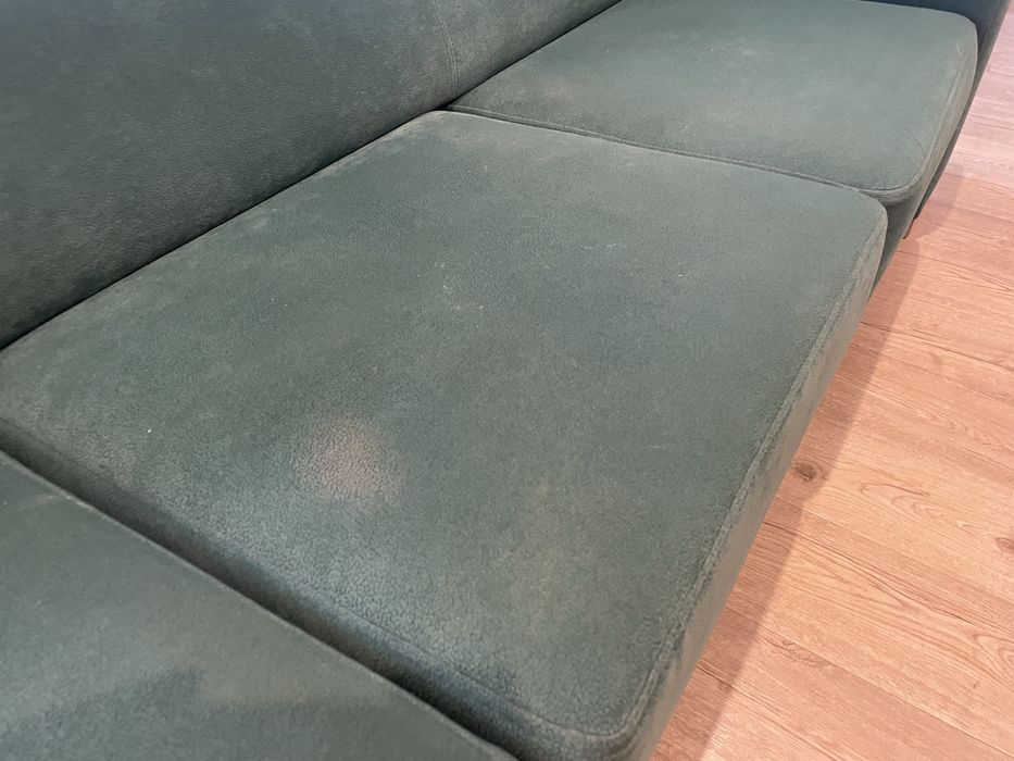 Zielona butelkowa sofa z funkcja spania z pufami i drewnianymi półkami