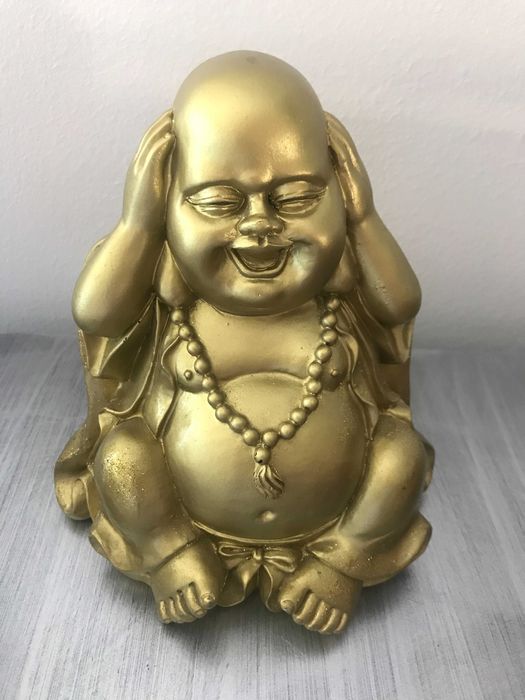 Buda dourado com mãos nas orelhas