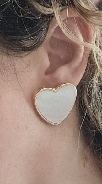 Brincos, de picos, com forma de coração branco delineado a dourado.