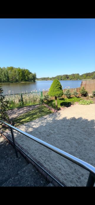 Bajkowy drewniany domek nad jeziorem z linią brzegową i prywatnym molo