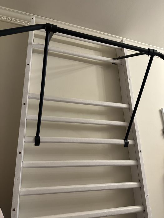 Biała drabinka gimnastyczna i drążek metalowy składany