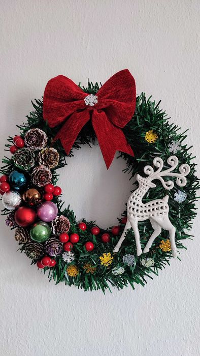 Wianek świąteczny na drzwi z czerwoną kokardą i białym reniferem