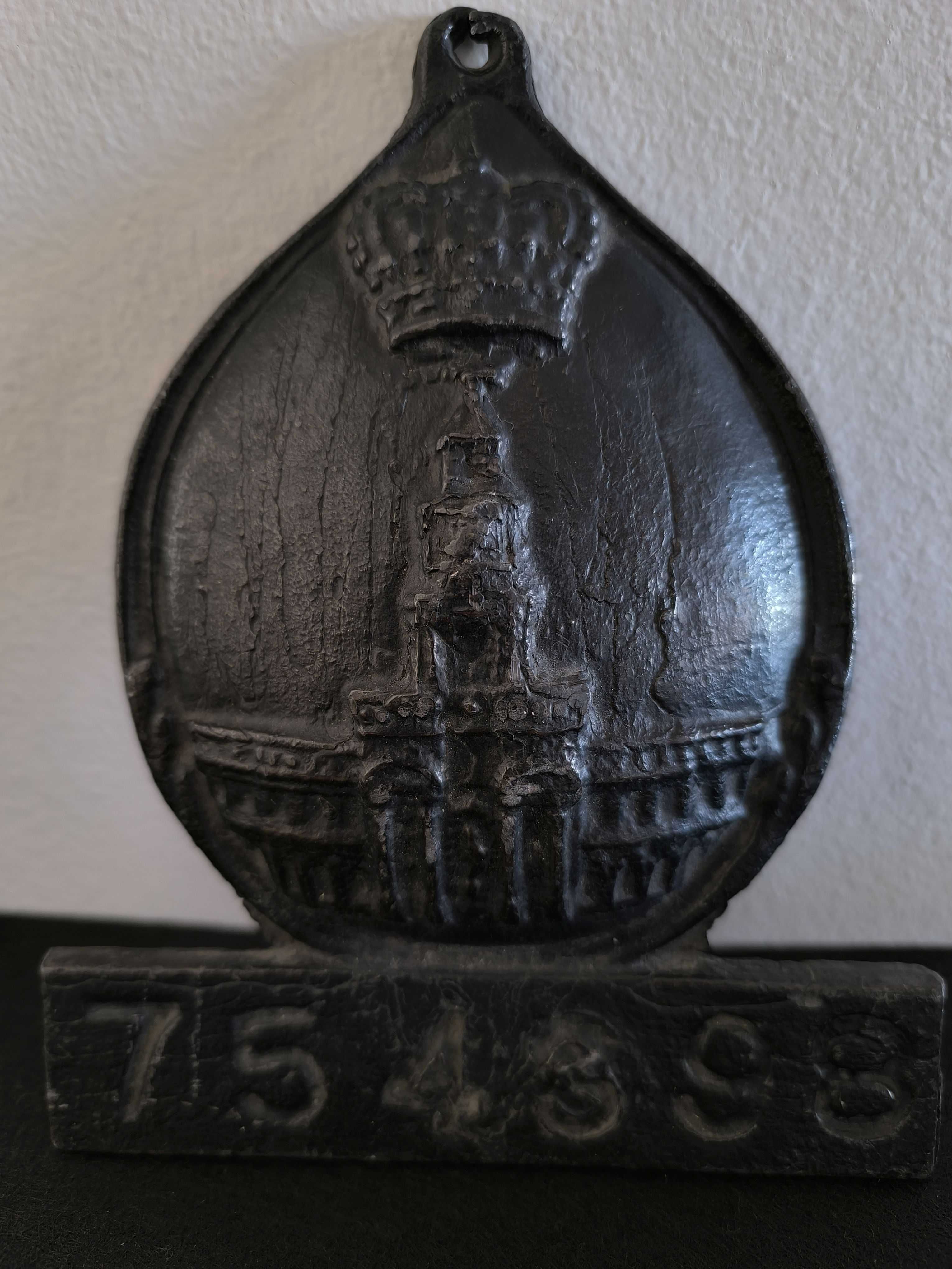 Placa de metal com o n.º 754398, marcada com o emblema da seguradora