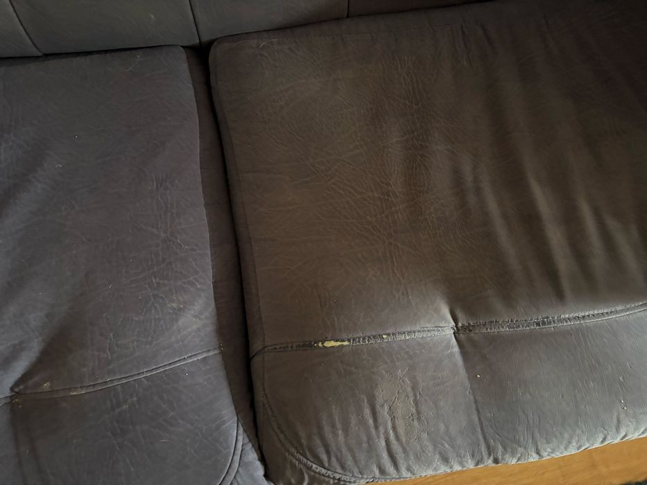 Sofá de sala, azul, com alguns anos e marcas de uso.