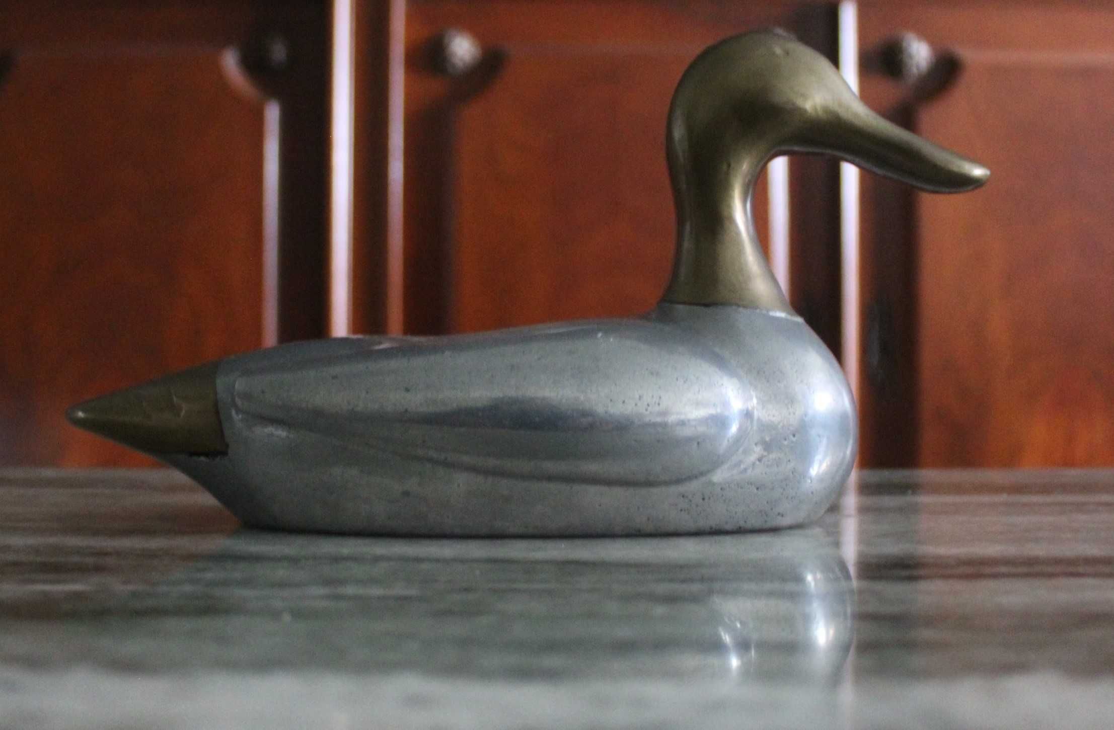 Estatueta vintage de pato, corpo prateado e a cabeça e cauda douradas.