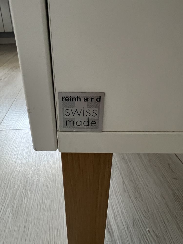 Mała biala szafka na nożkach w stylu skandynawskim.