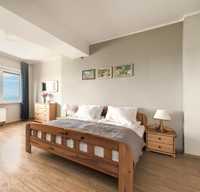 Drewniane łóżko 180x200 z dwiema szafkami nocnymi.