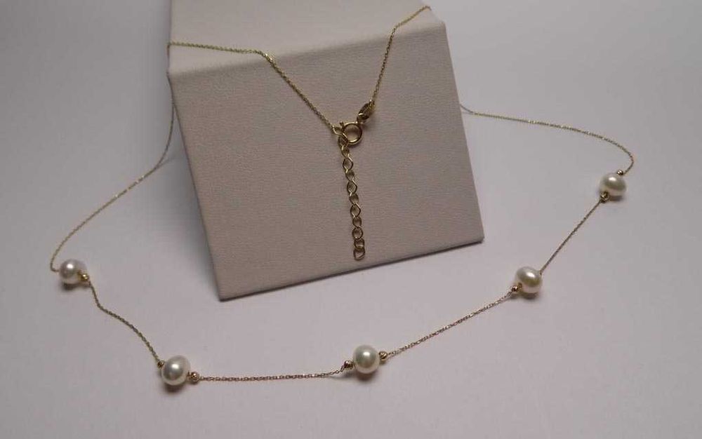 Delikatny złoty naszyjnik z perłami i diamentowanymi kulkami.