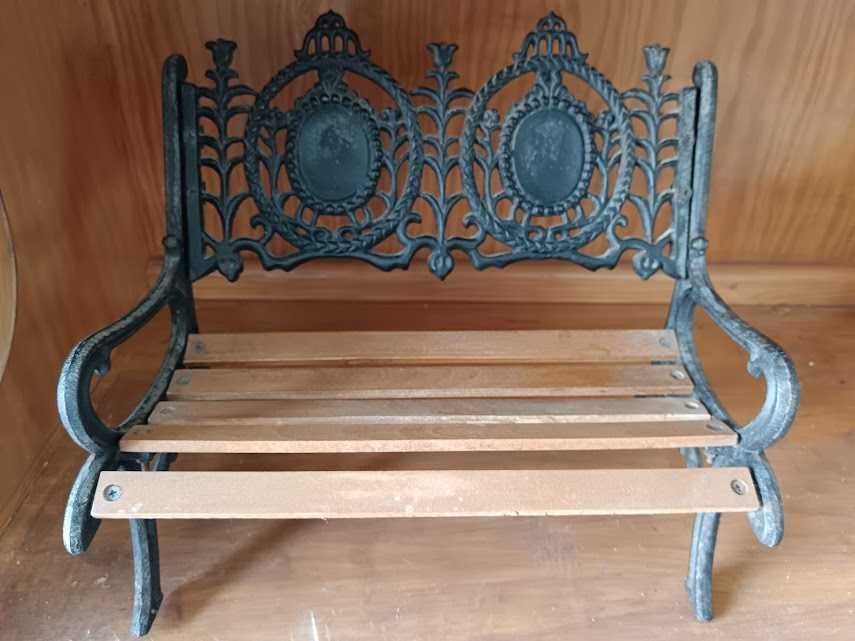 Banco de ferro e madeira, com bonecos sentados.