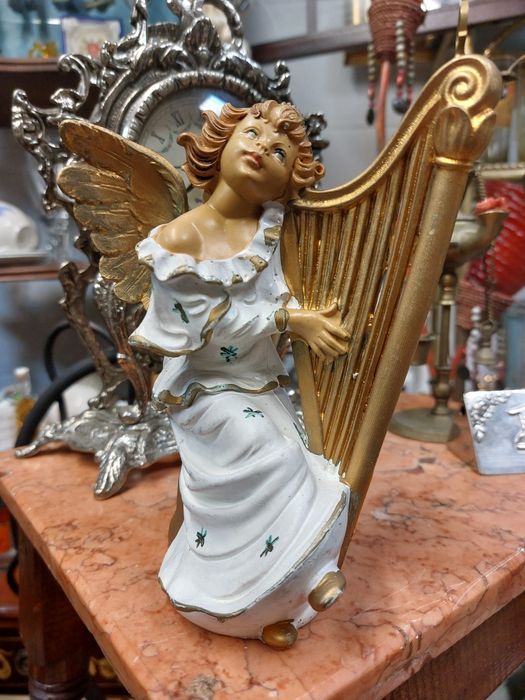 Estatueta em resina de um anjo a tocar harpa 

A estatueta aprese