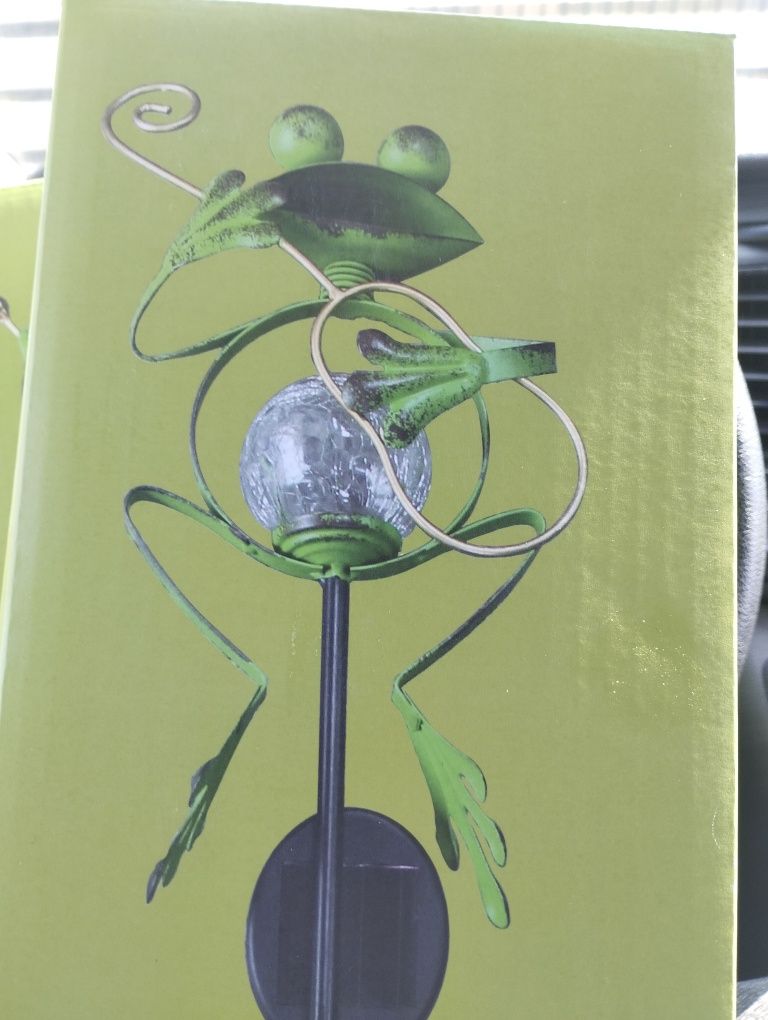 Lampa solarna z motywem żaby i instrumentu.