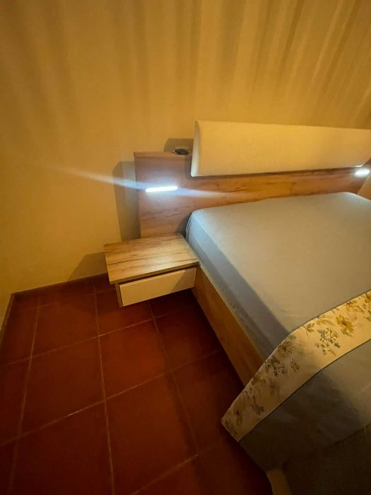 Cama de casal com mesas de cabeceira e iluminação
