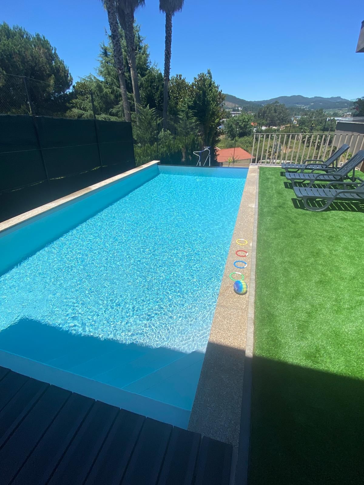 Espaço exterior com piscina e campo de jogos.