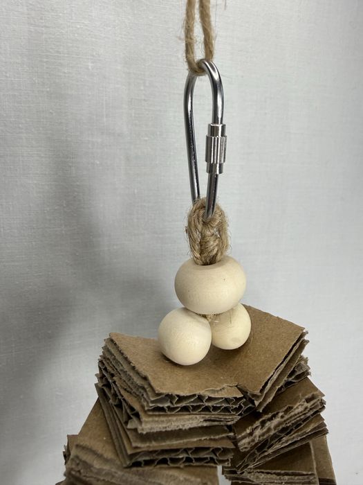 Mała huśtawka dla ptaków z tekturą i kulami wiklinowymi.