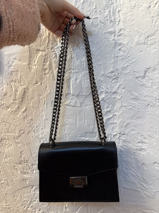 Czarna skórzana torebka damska z metalowym łańcuchem.