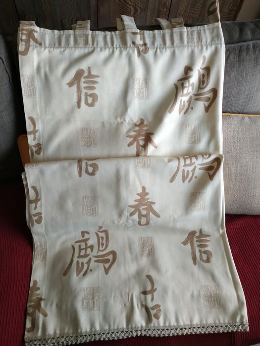 Cortinados e colcha bejes  com caracteres chineses.