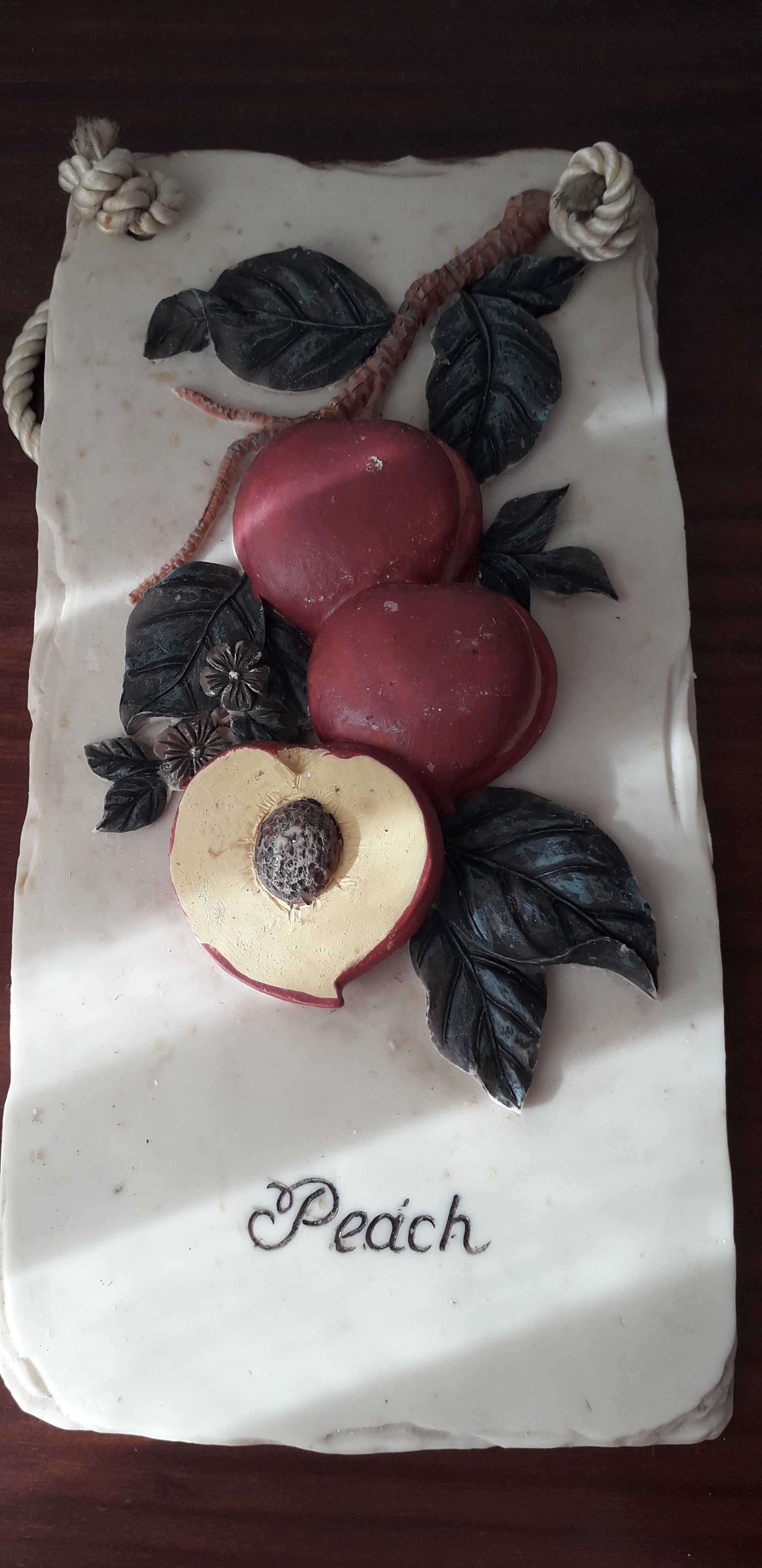 Placa em gesso, com palavra 'peach', com frutos e folhas verdes