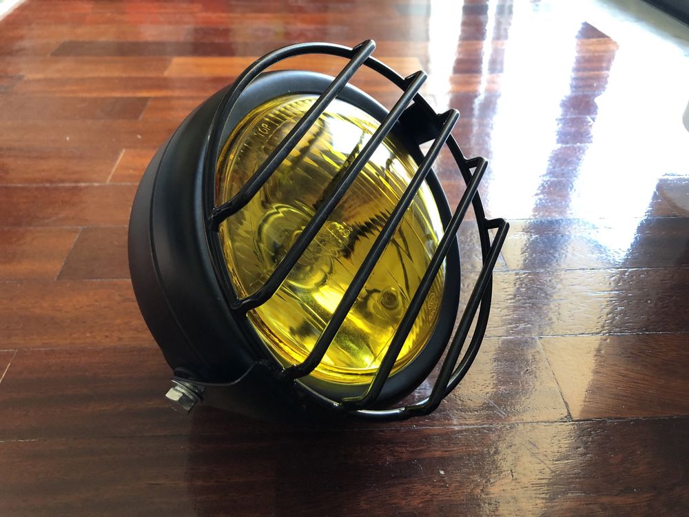 Farol frontal amarelo com grelha metálica dois apoios cafe racer