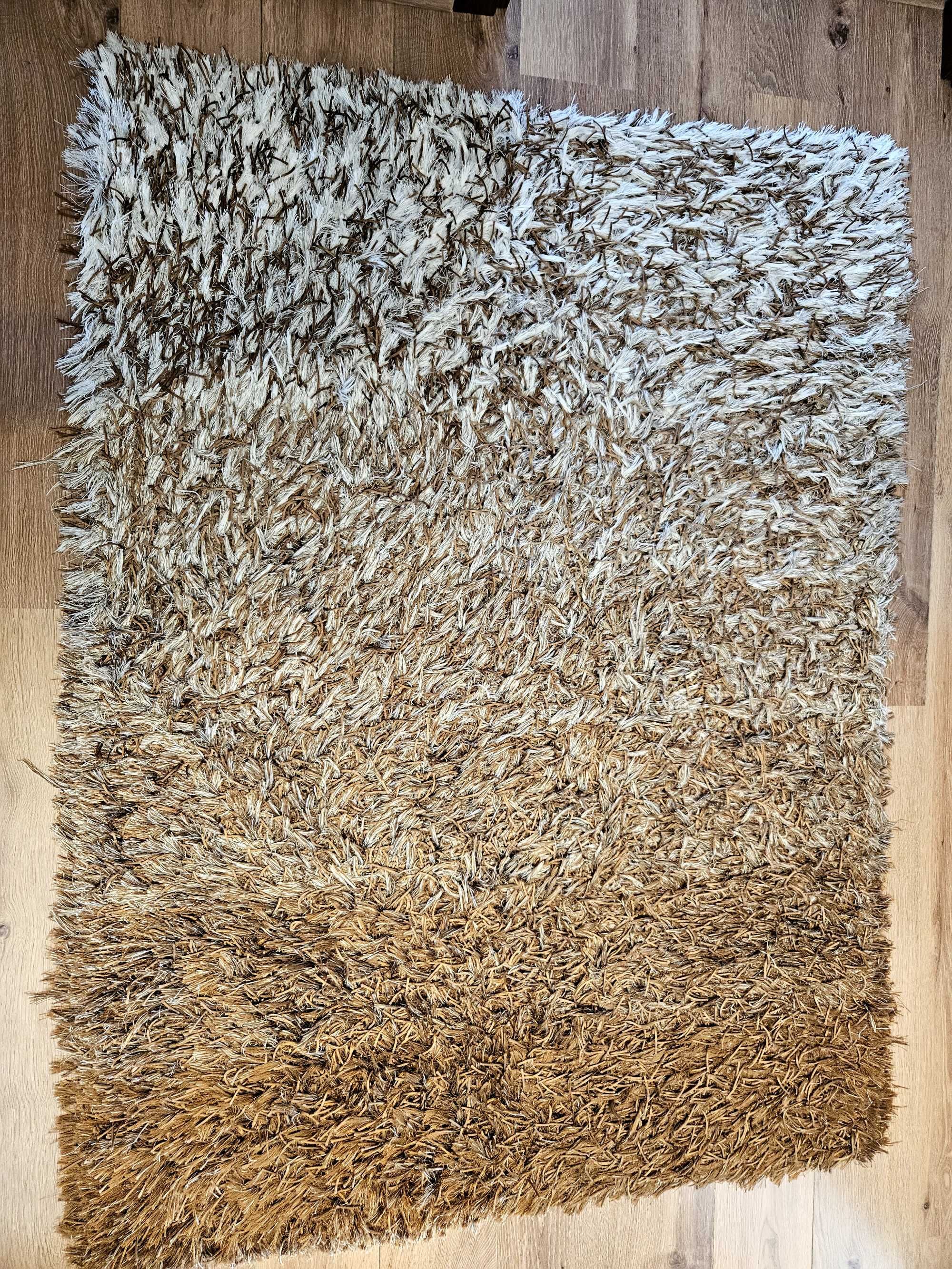 Carpete castanha, beje e cru, de pêlo.